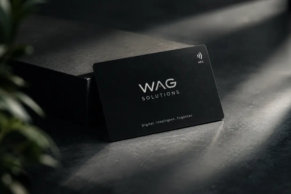 Schwarze Visitenkarte mit Firmenschriftzug und NFC-Symbol auf dunklem Untergrund